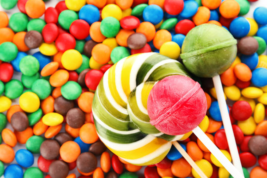 Lollipops and colorful candies as background, top view