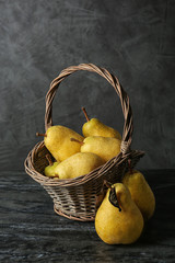 Basket with fresh ripe pears on table against gray background
