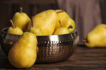 Fresh ripe pears on wooden table against blurred background