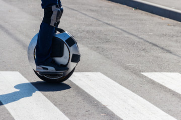 Electric unicycle. Man rides on mono wheel on zebra crossing © olyasolodenko