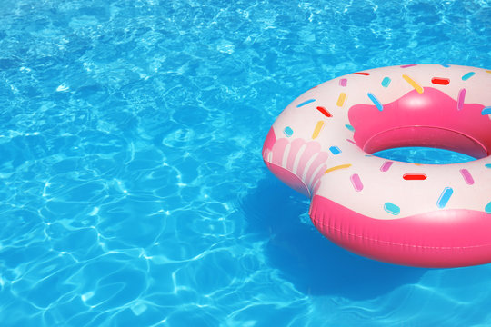 Inflatable ring floating in swimming pool on sunny day. Space for text