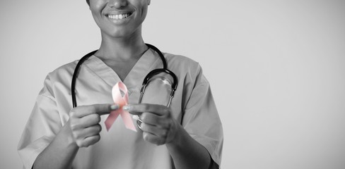 Smiling nurse holding breast cancer awareness pink ribbon with