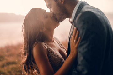 Close up of just married couple standing outside and kissing. Emotional moment on their wedding day. - Powered by Adobe