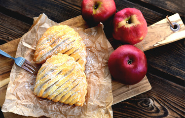 Easy Apple Turnovers (German name is Apfeltaschen) on brown paper with fresh red apples on wooden...