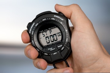 Male hand holding stopwatch on blurred background