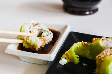 Sushi roll with eel and avocado, chopsticks. Traditional Japanese meal.