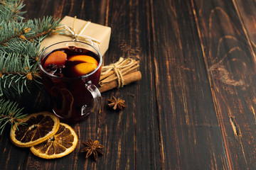 Mulled wine, a gift and spices on the table next to the tree. The concept of Christmas and New Year, decor.