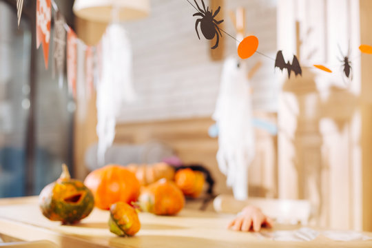 Ready for Halloween. Table with paper decorations and bright pumpkins lying on it ready for Halloween children party