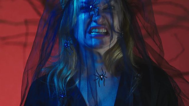 4k, slow motion, Halloween. Woman in costume of a terrible witch, swears looking at the camera, close-up