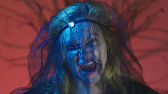 4k, slow motion, Halloween. Woman in costume of a terrible witch, swears looking at the camera, close-up