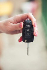 Key from the car in a female hand. Car seller. Opening and signaling