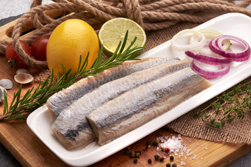 Delicious Atlantic salted herring with onion on the cutting board. Rustic style,