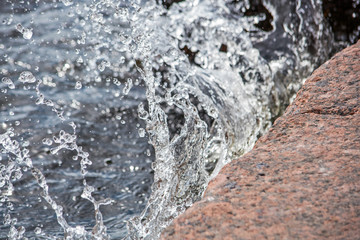 Waves break into drops on the stone shore