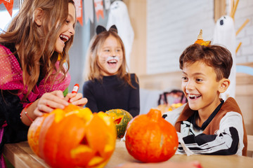Fototapeta premium Cheerful children. Two sisters and one brother wearing Halloween costumes feeling happy and cheerful celebrating together