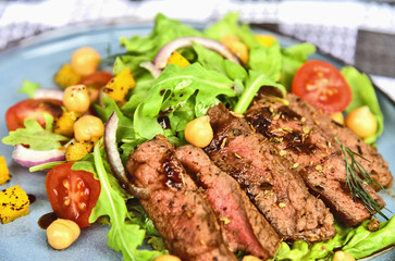 Steak Salad with Honey Soy Pan Sauce on blue dish..Beef salad with Arugula and chickpeas.