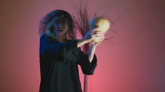 4k, slow motion, Halloween. A woman in the suit of a terrible witch dances with a pumpkin in her hands. space for copying