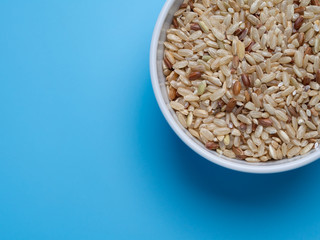 brown rice in white cup on a blue background