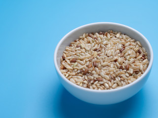 brown rice in white cup on a blue background