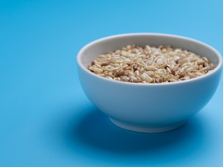 brown rice in white cup on a blue background