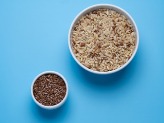 brown rice and flax in white cups on a blue background