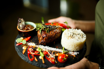 Steak with rice and vegetables on a black plate