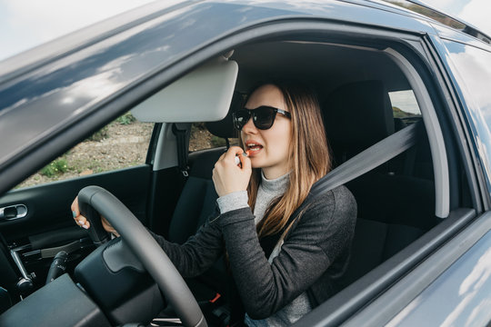 Cute Young Girl Driver Paints Lips Inside The Car.