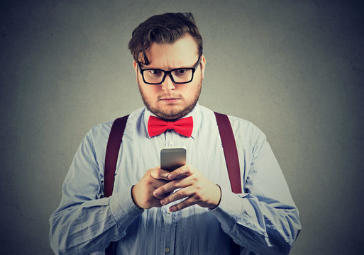 Confused serious looking man thinking what to reply to received text message on cell phone