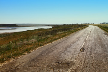 Old a little damaged asphalt road in steppe or field, industrial transportation image