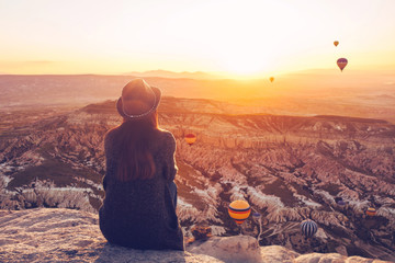 A girl in a hat on top of a hill in silence and loneliness admires the calm natural landscape and...