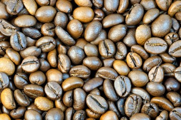 Grains of natural roasted coffee, for the preparation of a delicious refreshing drink. Beautiful brown background color.