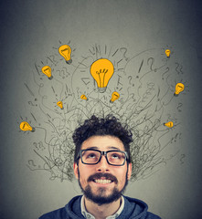 Excited man looking up at many ideas light bulbs above head