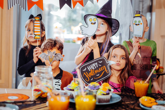 Pictures and signs. Cute and funny boys and girls wearing costumes holding pictures and signs devoted to Halloween