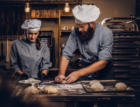 Chef teaching his assistant to bake the bread in a bakery.