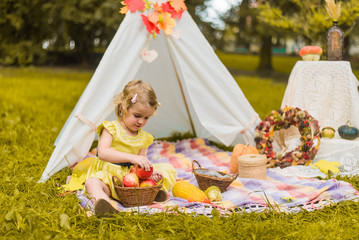 Little girl lying and playing in a tent, children's house wigwam in park Autumn portrait of cute...