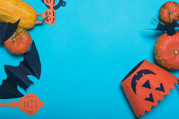 Halloween, decoration and scary concept - black paper bats, pumpkins over blue background. Free place for text.
