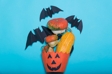 Halloween, decoration and scary concept - black paper bats, pumpkins over blue background. Free place for text.