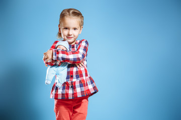 Cute little girl with doll on blue background