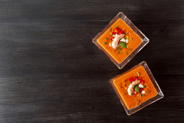 Soup gazpacho with shrimps. Italian Cuisine. Two transparent bowls with soup on a black background. Top Vieux. Copyspace.