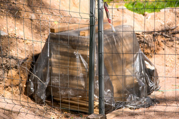 Metal gates of the construction site behind which the boards are stored