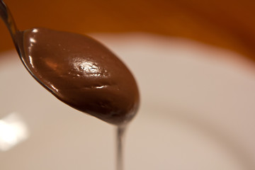 sweet brown milk chocolate paste on spoon top view isolated on white background. diet nutrition wallpaper.
