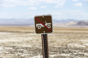 Old no off road driving sign with Mojave desert dry lake in background.  Shot near Zzyzx in Southern California.  