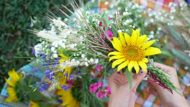 Female hands make a wreath of summer wildflowers
