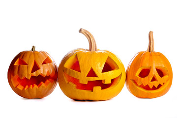 Three orange pumpkins carved into creepy and funny Jack o Lantern isolated on white background. All hallows night. Copy space, close up, top view. Halloween party decoration. Trick or treat concept.