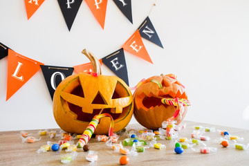 Few orange pumpkins of different size carved into Jack o Lantern on wooden table. Background, copy...
