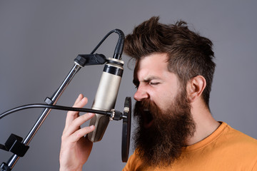Bearded man singing with microphone. Concert&music concept. Brutal bearded guy singer with microphone on stage. Male lead vocalist singing in recording studio. Vocalist singing in condenser microphone