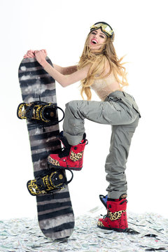 Snowboard girl. Winter leisure. Extreme sport. Attractive athletic woman in ski mask holds snowboard. Winter time. Ski mask. Snowboard girl in safety glasses standing on dollars. Sport concept. Money.