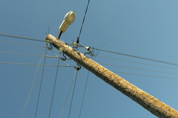 pole with wires of a power line with a lantern on a blue sky background