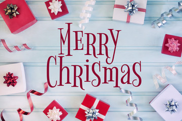 Fototapeta premium Gifts in beautiful red and white boxes. The boxes lie on a light blue background in a circle. In the center there is an inscription of Merry Christmas.
