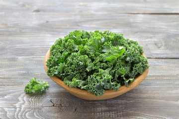 Fresh green curly kale leaves on a wooden table. selective focus. rustic style. healthy vegetarian food