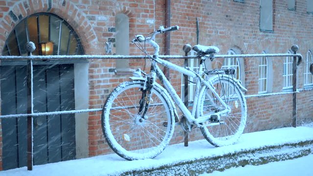 First snow in city. Snow covered bicycle on street